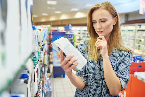 mujer leyendo los valores nutricionales de una caja de leche