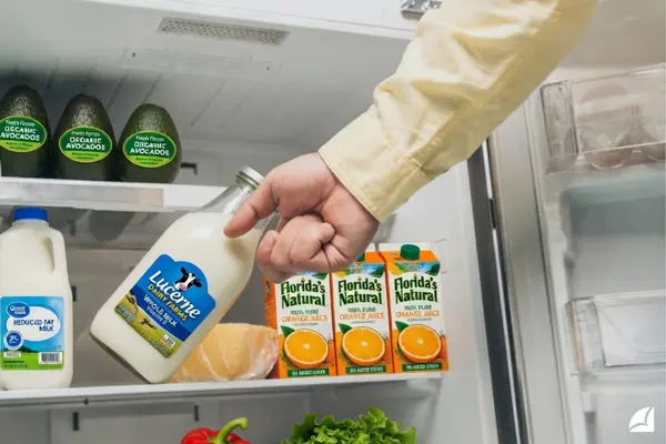 Botella de leche y alimentos en el refrigerador con adhesivos para etiquetas resistentes al frío y la humedad